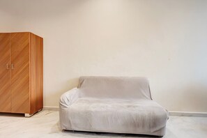 A room with a white sofa and a wooden wardrobe. - Super Townhouse Dewas Bus Terminal (Ujjain)