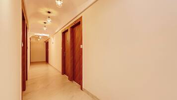 Un corridoio d'hotel con porte in legno, pavimento chiaro e luci a soffitto.