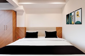 A modern bedroom with a bed, wooden wardrobe, and artwork on the wall. - Super Townhouse Dewas Bus Terminal (Ujjain)