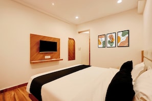 A hotel room with a bed, a flat-screen TV mounted on a wooden panel, and three framed artworks on the wall. - Super Townhouse Dewas Bus Terminal (Ujjain)