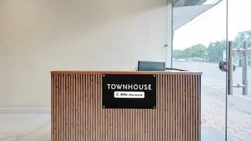 Un mostrador de recepción con un cartel que indica 'TOWNHOUSE' y servicios 'YO-Serviced'.