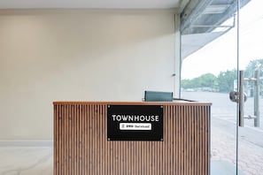 A reception desk with a sign indicating 'TOWNHOUSE' and 'YO-Serviced' amenities. - Super Townhouse Dewas Bus Terminal (Ujjain)