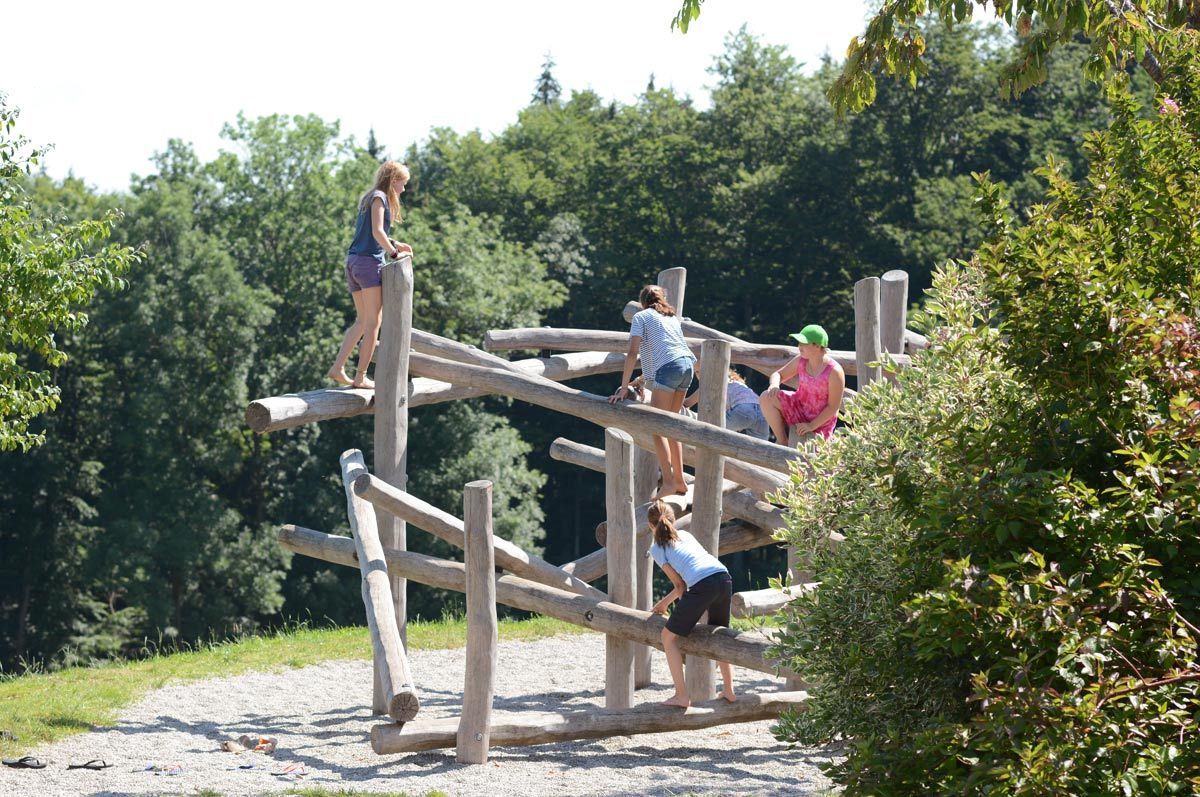Eine Gruppe von Menschen nutzt eine hölzerne Kletteranlage im Freien.