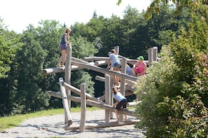 A group of people engaging with a wooden climbing structure in an outdoor setting. - "Kräuterwiese" House, 535 square meters (Frasdorf)