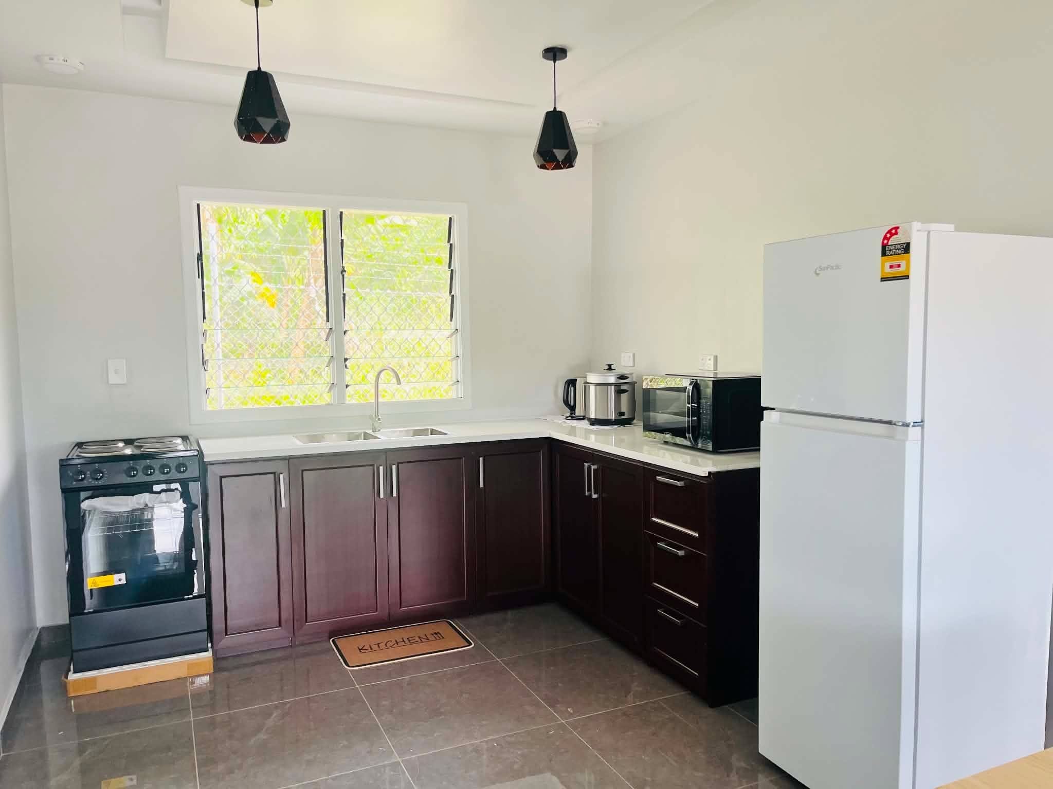 Una cocina equipada con estufa, horno, microondas y refrigerador.