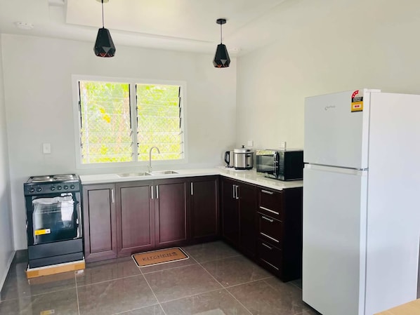 Una cocina equipada con estufa, horno, microondas y refrigerador.