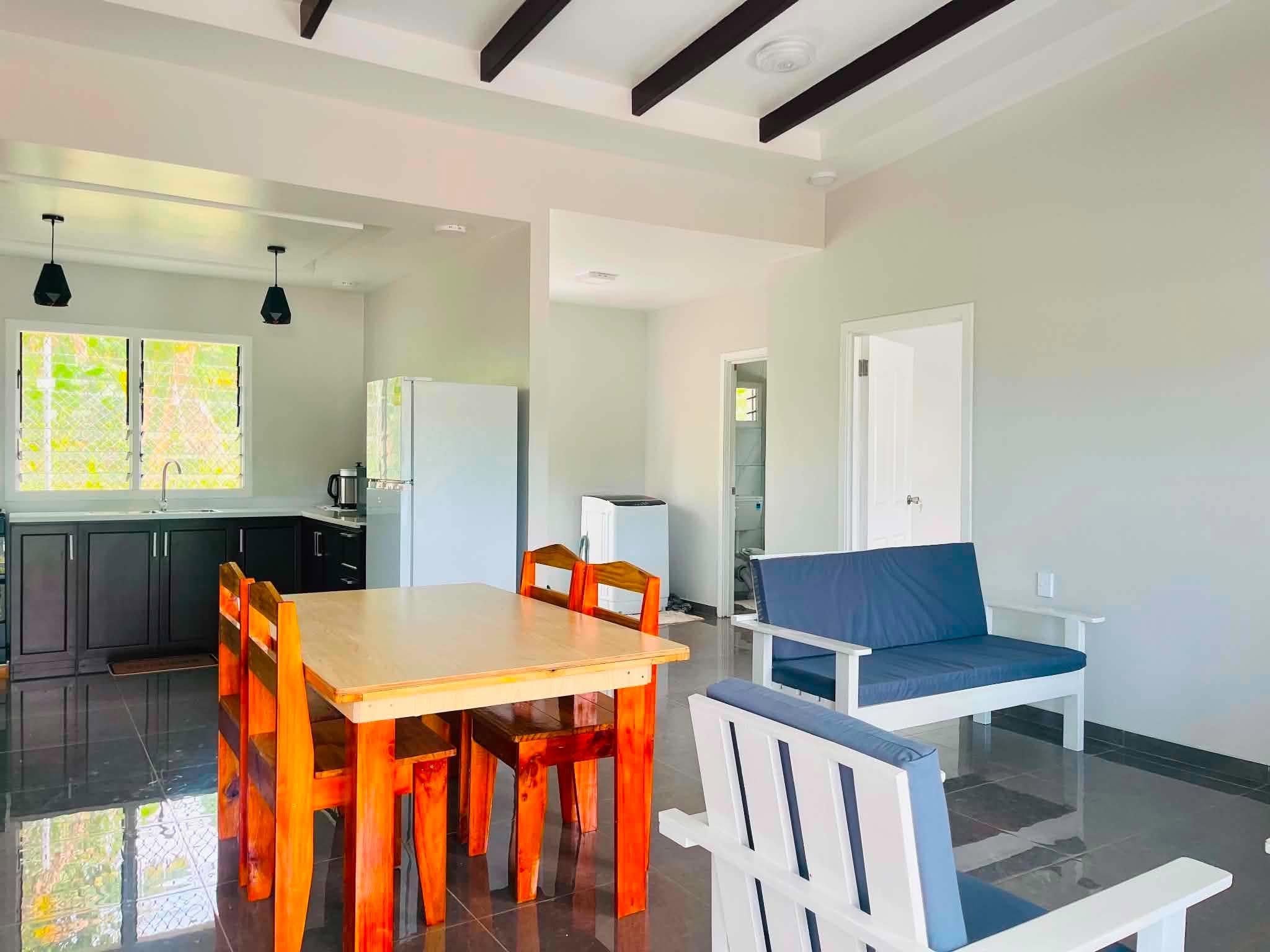 A modern kitchen with dark cabinets, a wooden dining table, and a blue cushioned bench.