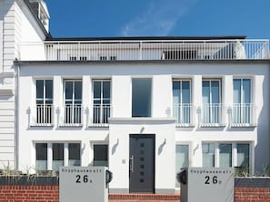 Ein modernes, zweistöckiges Gebäude mit flacher Fassade, weißer Außenwand und mehreren Balkonen.
