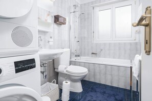 Casa de banho moderna com sanita, lavatório, chuveiro e banheira.