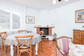 Uma sala de jantar com mesa redonda e cadeiras, lareira e sofá.