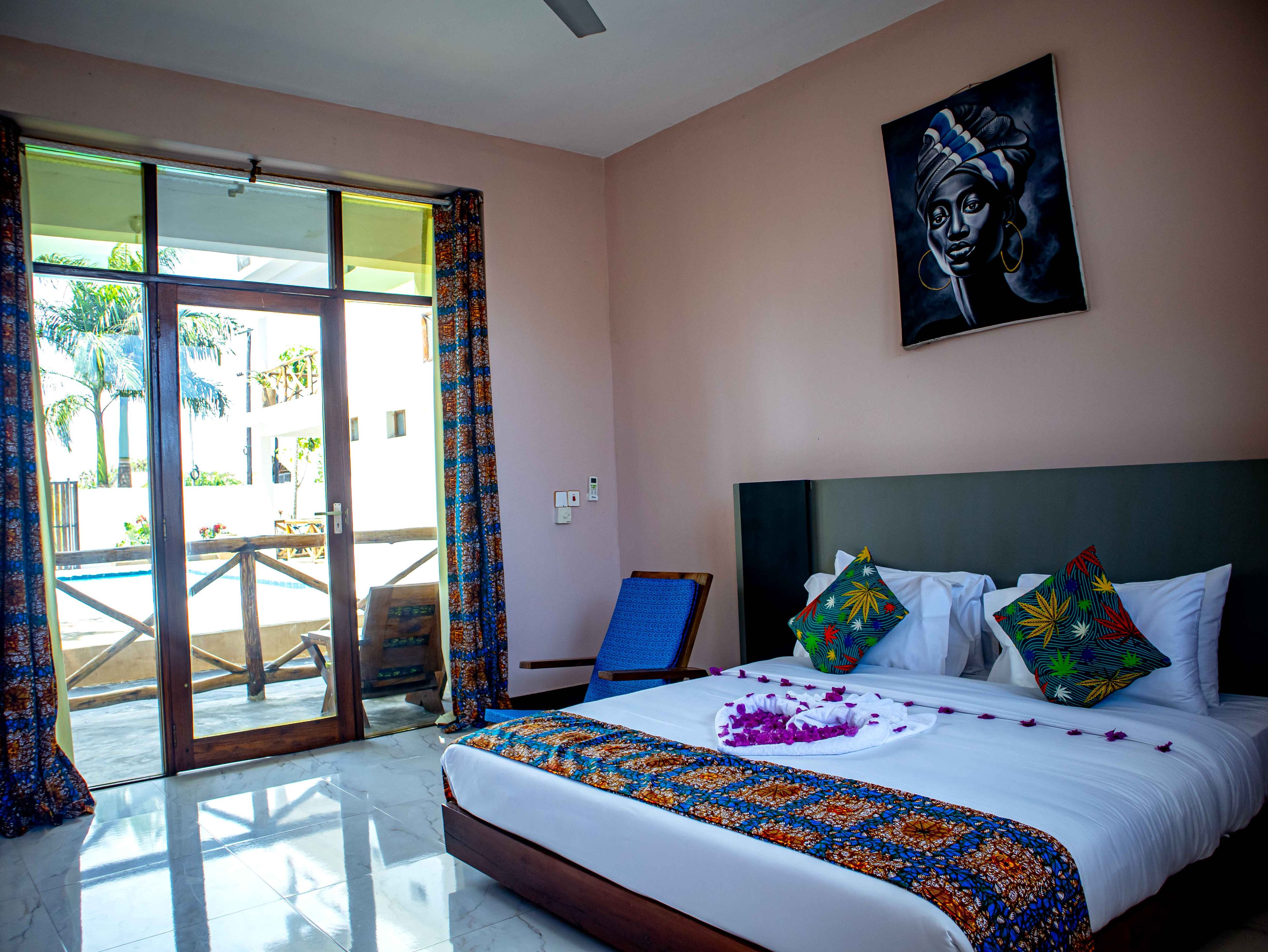A hotel room with a bed, a painting, and a view of a pool area.