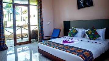 A hotel room with a bed, a painting, and a view of a pool area.