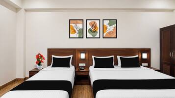 A hotel room with two beds, a nightstand with a lamp, and artwork on the wall.