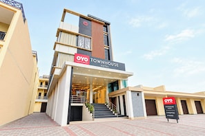 Un hotel moderno con un letrero llamativo que dice 'OYO TOWNHOUSE HOTEL' y una escalera que lleva a la entrada.
