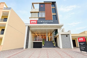 Una entrada de hotel moderna con un letrero que dice 'OYO TOWNHOUSE HOTEL' y señales que indican 'RECEPCIÓN' y 'HABITACIONES'.