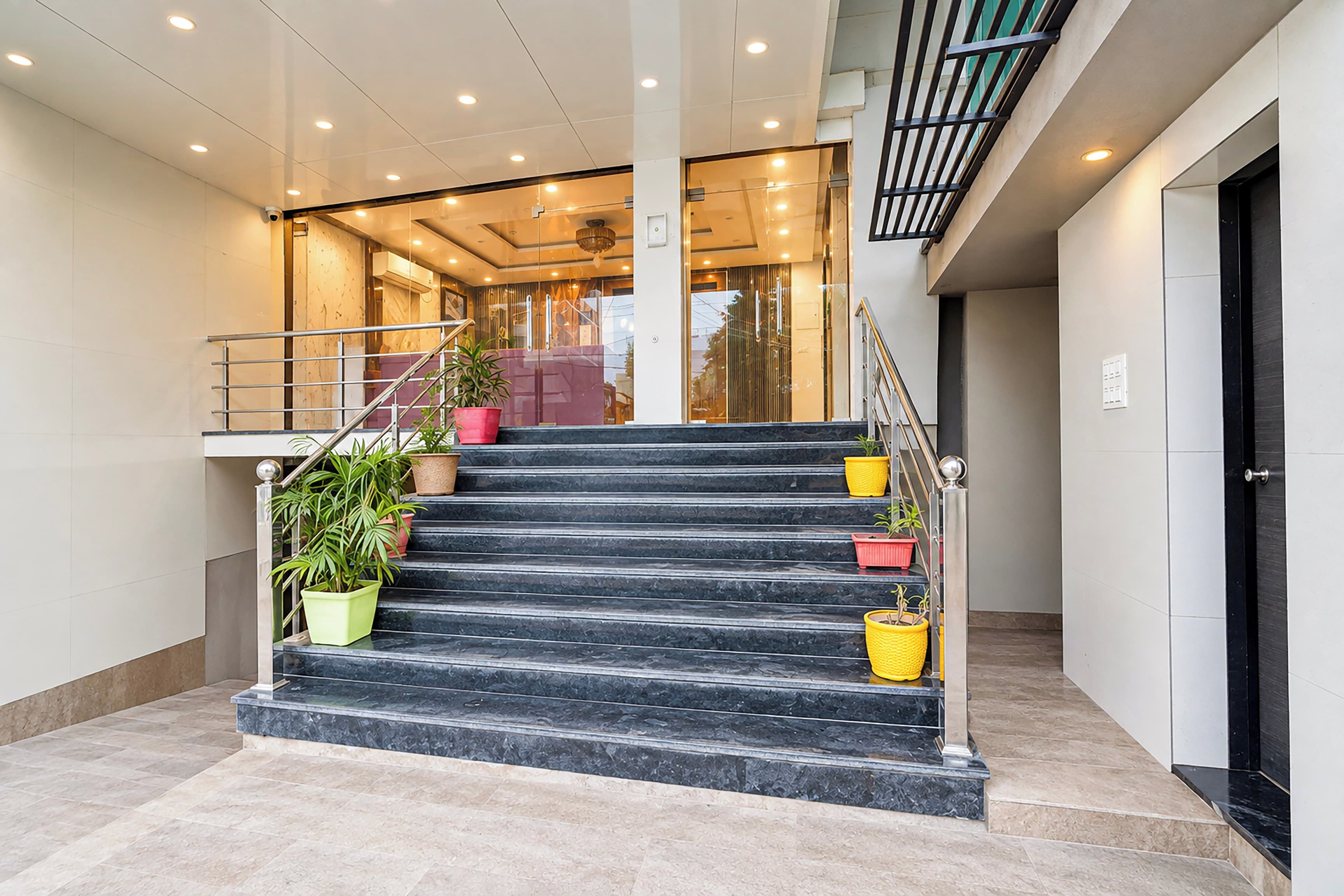 Una escalera con escalones de mármol que conduce a una zona de recepción con puertas de cristal y un interior moderno.