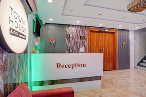 Una zona de recepción con un cartel que dice 'Reception', una puerta hacia el 'Banquet Hall' y un cartel que indica 'Town House Oyo-Service'.