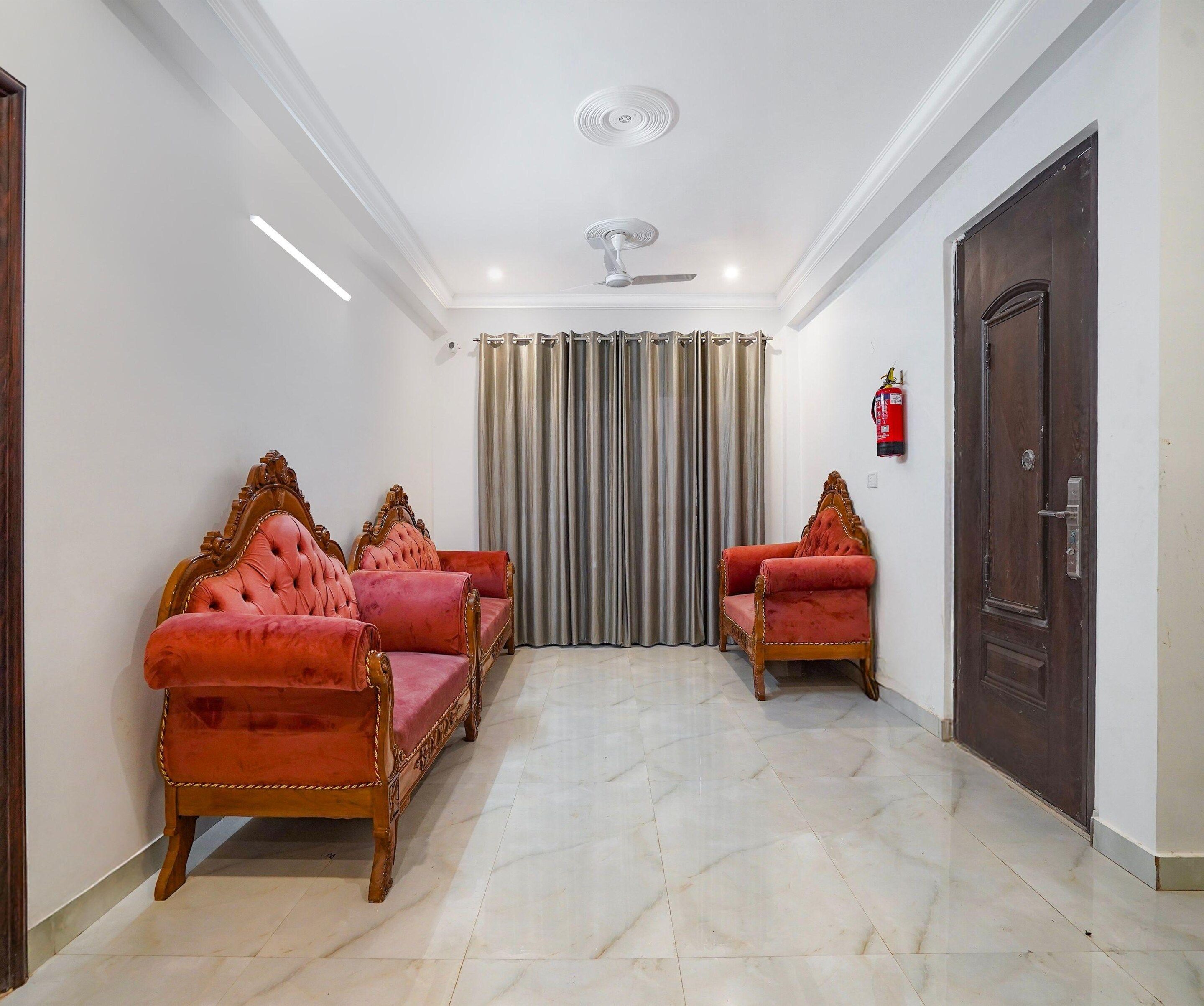 A hallway with a ceiling fan, a fire extinguisher, and two ornate red sofas.