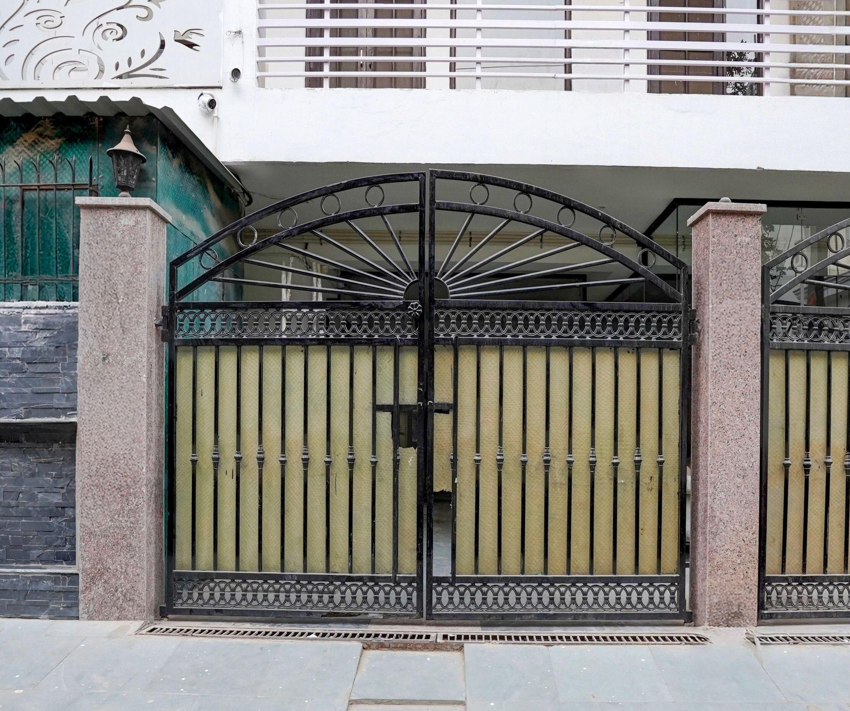 Une entrée fermée par un portail en métal agrémenté d’éléments décoratifs.