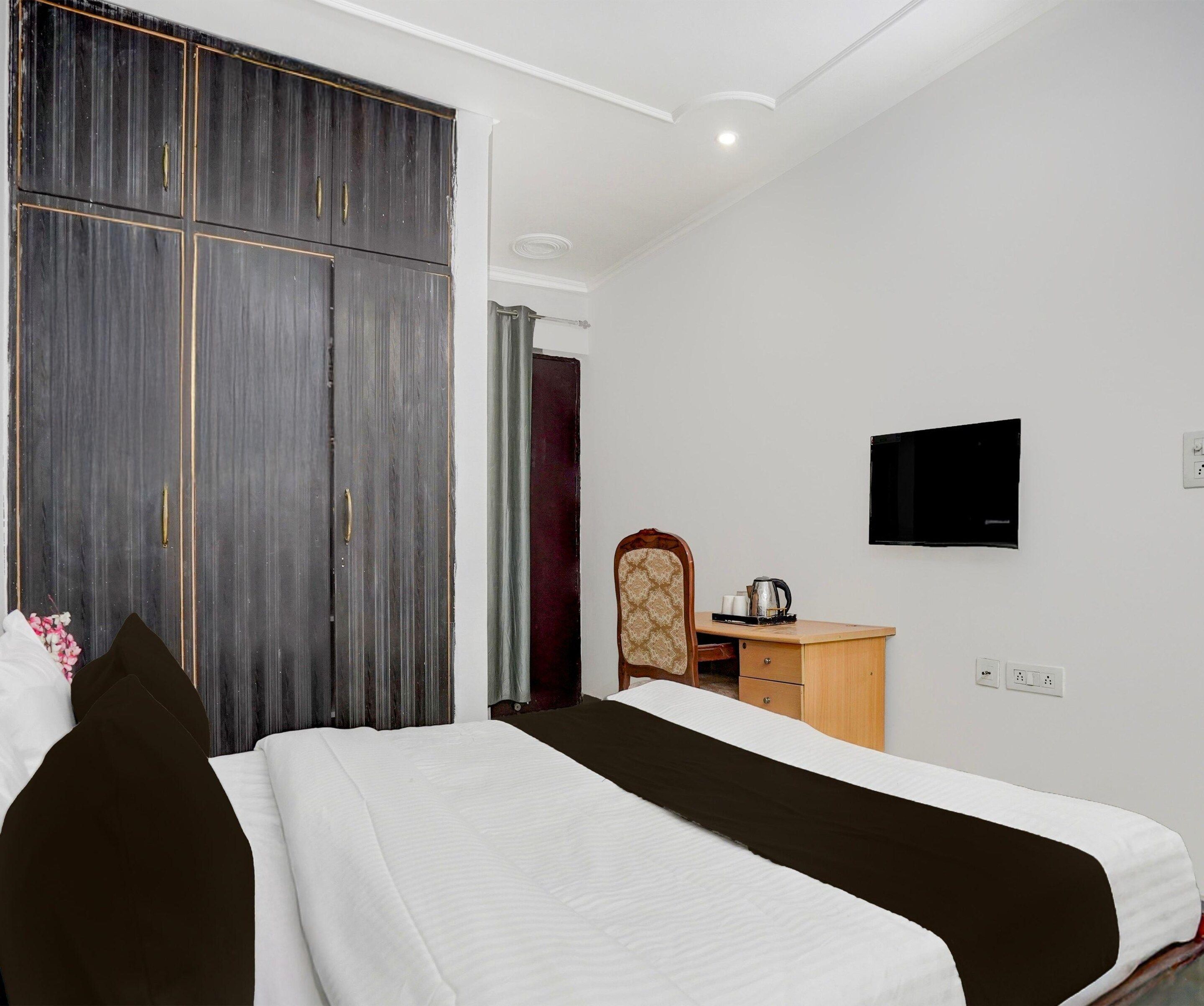 Une chambre d’hôtel équipée d’un lit, d’une armoire, d’une télévision et d’un bureau avec une bouilloire.