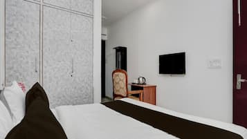 A hotel room with a bed, a wardrobe, a desk, a chair, a television, and a door.