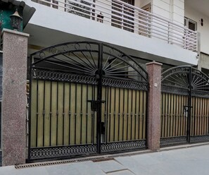 A gated entrance with a metal gate and a balcony above. - Deluxe Townhouse Huda Market (Gurugram)