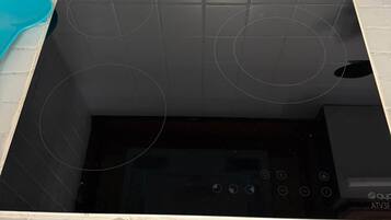 A kitchen with a black stove, white tiled walls, and a wooden countertop.