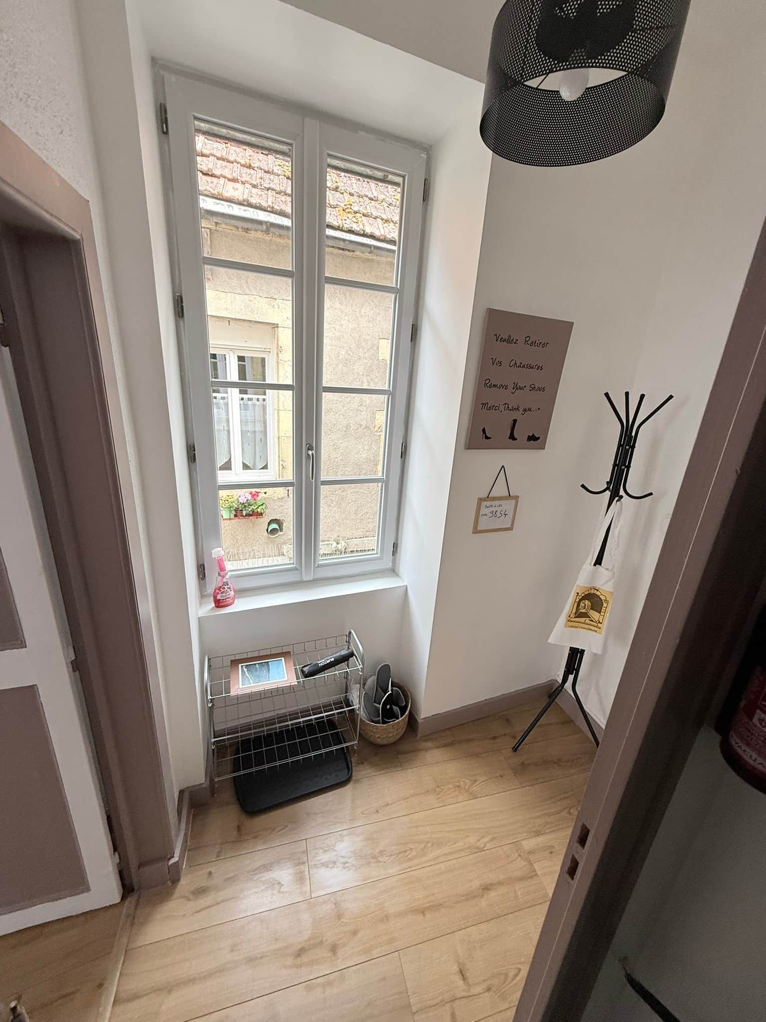 A room with a window, a drying rack, a shoe rack, and a wall-mounted sign.