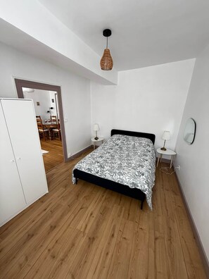 A bedroom with a bed, bedside tables, a wardrobe, and a hanging light fixture.