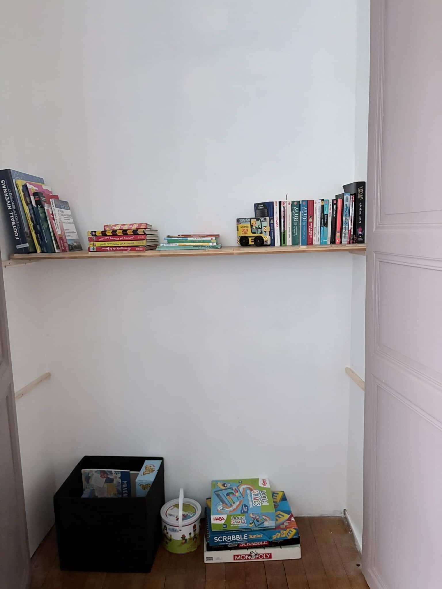 Ein kleines Zimmer mit einem Bücherregal voller Bücher und einem Monopoly-Spiel auf dem Boden.