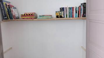 Ein kleines Zimmer mit einem Bücherregal voller Bücher und einem Monopoly-Spiel auf dem Boden.
