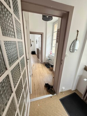 A hallway with a door leading to a room, a mirror on the wall, and a rug on the floor.