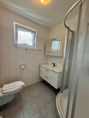 A bathroom with a toilet, sink, mirror, and shower. - Mountain View Studio "Hana" - Adler Resort (Kaprun)