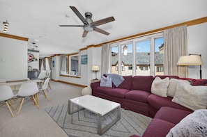 A living room with a ceiling fan, a sofa, a coffee table, and a dining area with chairs. - Charter Ski In Ski Out 2BR (Beaver Creek)