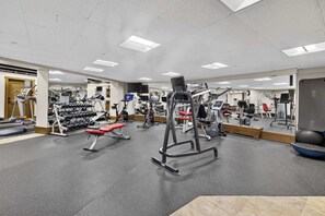 A gym with various exercise equipment, mirrors, and a weight rack. - Charter Ski In Ski Out 2BR (Beaver Creek)