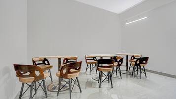 Un intérieur moderne au design minimaliste, avec une table ronde centrale entourée de six chaises dotées d’un dossier au design original et ajouré.