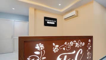 Uma área de recepção com uma placa indicando 'TOWNHOUSE OYO-Serviced' e um painel decorativo com 'F.C'.
