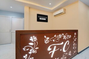 Un área de recepción con un letrero que indica 'TOWNHOUSE OYO-Serviced' y un panel decorativo con 'F.C'.