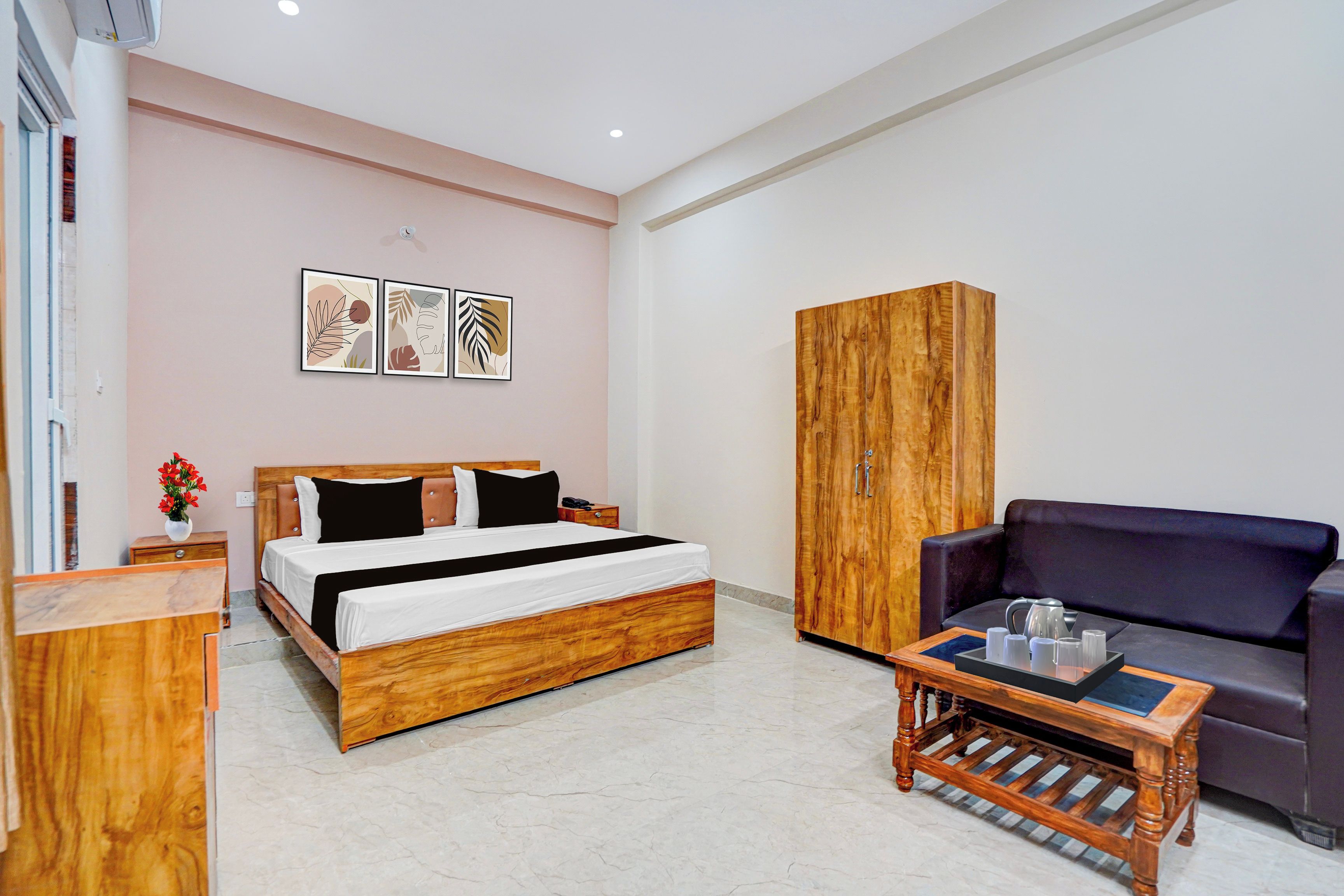 A hotel room with a wooden bed, a sofa, a wooden cabinet, and a coffee table.