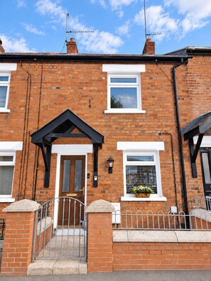 A two-story brick house with a front door, a small porch, and a metal gate. - Cosys Corner – Spacious 3-Bedroom Belfast Home (Belfast)