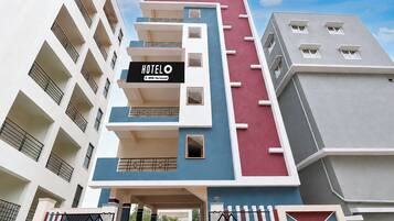 A multi-story hotel building with a sign indicating it is serviced by OYO.