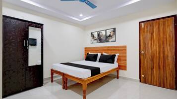 A bedroom with a bed, a ceiling fan, a wooden wardrobe, and a door.