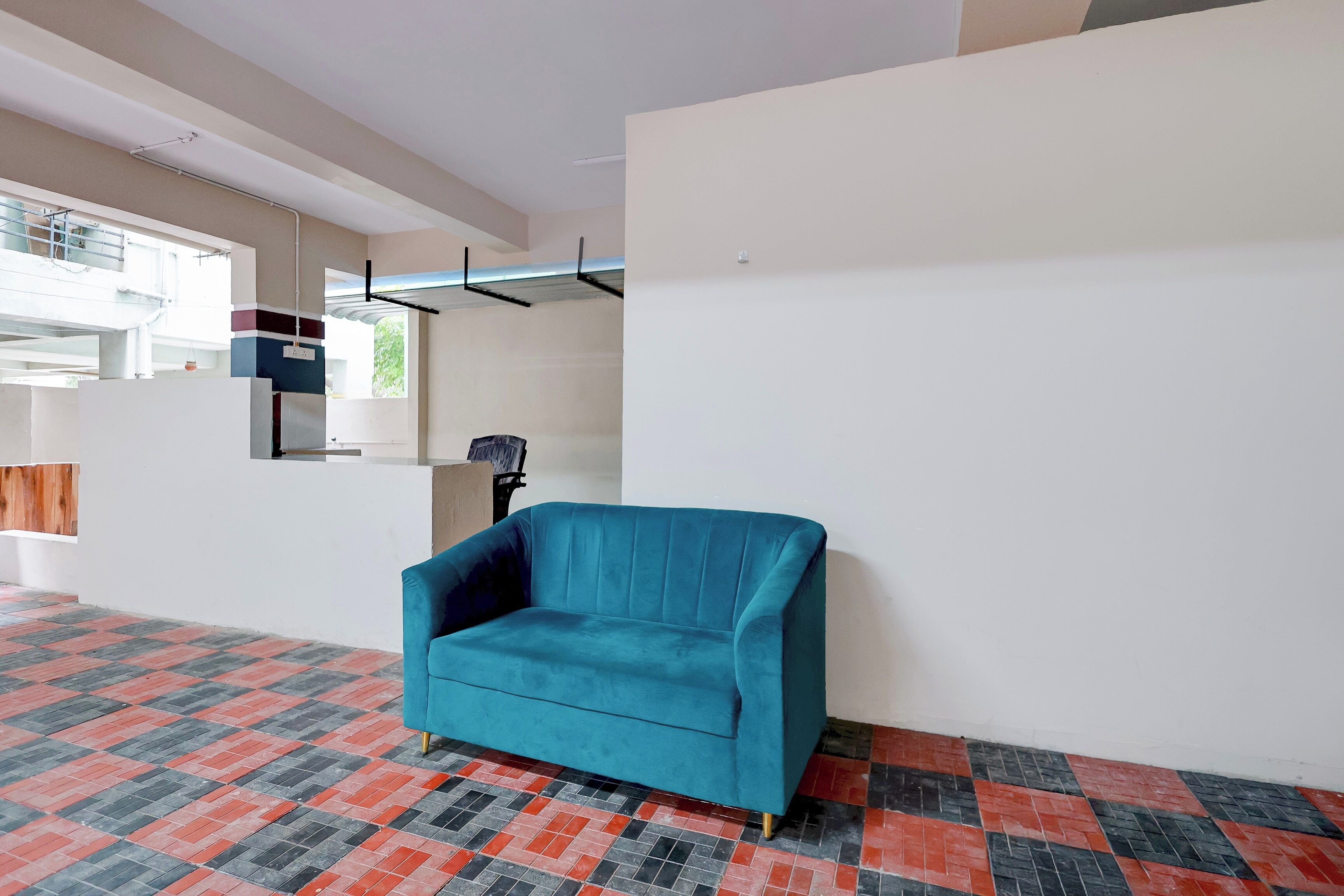 A room with a teal sofa, patterned floor, and a window with a view.