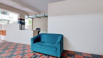 A room with a teal sofa, patterned floor, and a window with a view.