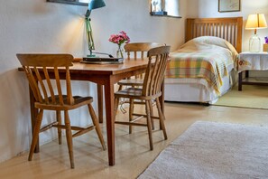 Un dormitorio con cama, mesita de noche, lámpara y escritorio con sillas.