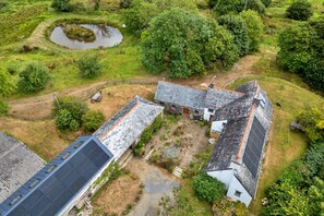 Ein ländliches Anwesen mit Teich, einem Kleinwagen und einem Haus mit Satteldach.