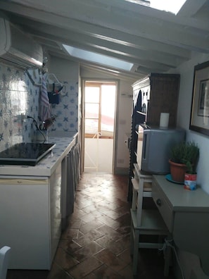A narrow kitchen with a tiled backsplash, a window, and a door leading to a balcony. - Top floor flat with terrace overlooking the duomo (Firenze)