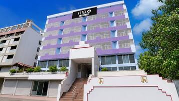 A modern hotel building with a sign indicating it is serviced by Oyo.