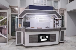 A hotel reception desk with a sign reading 'HOTEL O' and 'OYO-Serviced'.