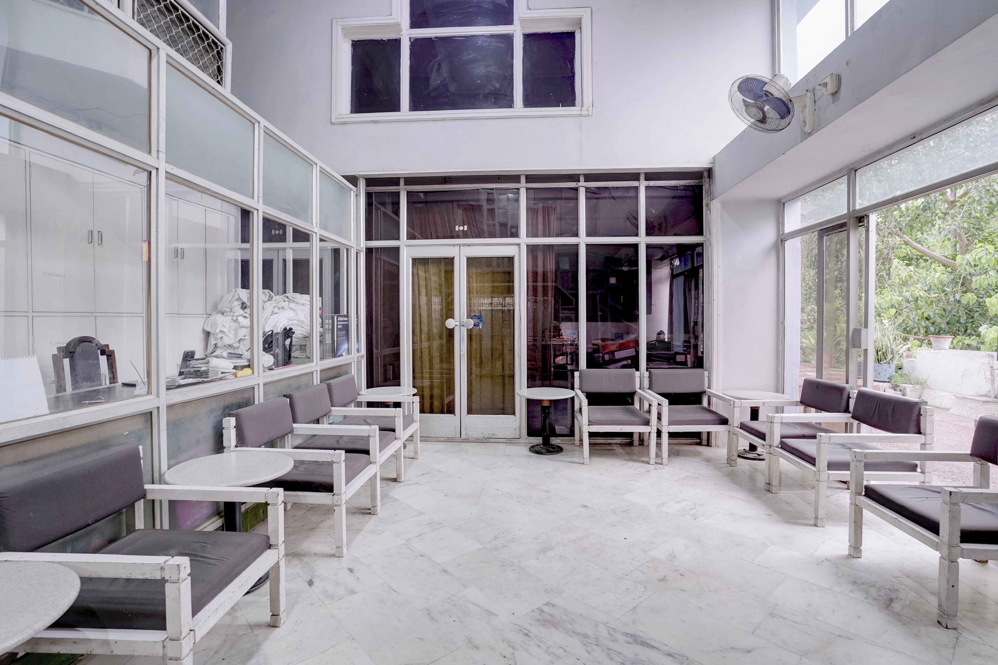 A cafe with white furniture, large windows, and a view of the outdoors.